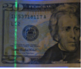 $20 bill glowing green under ultraviolet (UV) light